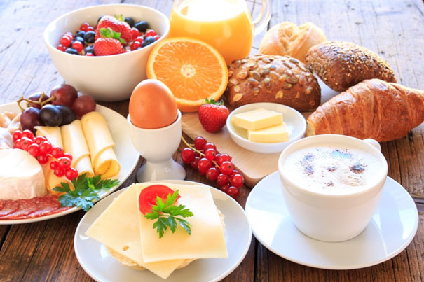 Einladung zum Wirtschaftsfrühstück - Beispielbild mit Cappuccino, Brötchen, Croissant, Ei, Butter, Käse und Obst